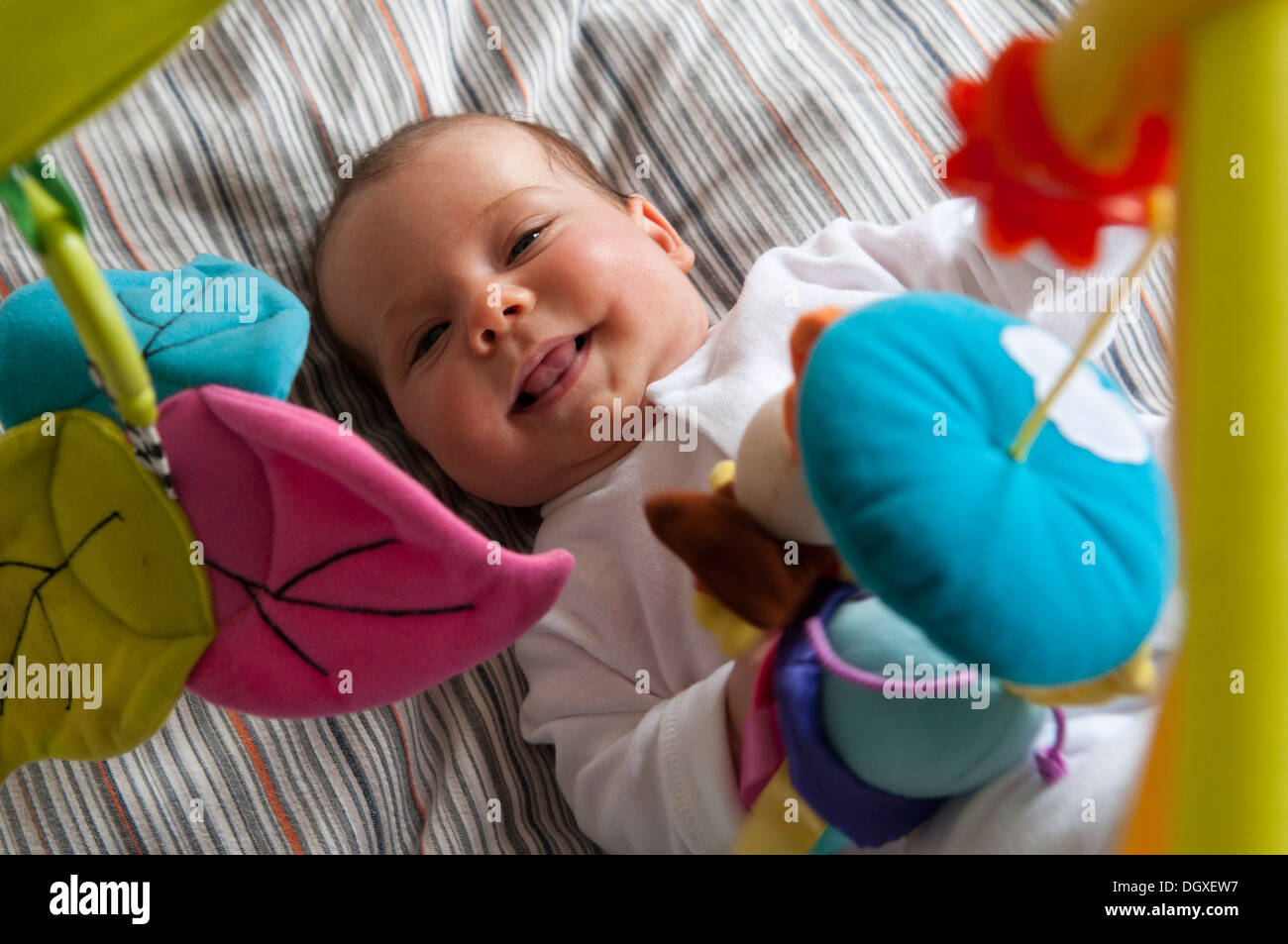 Little baby ragazza sorridente che giace sotto un gioco palestra Foto Stock