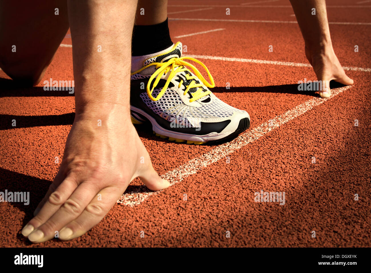 Runner in uno stadio è in posizione di avviamento con le mani sulla linea Foto Stock