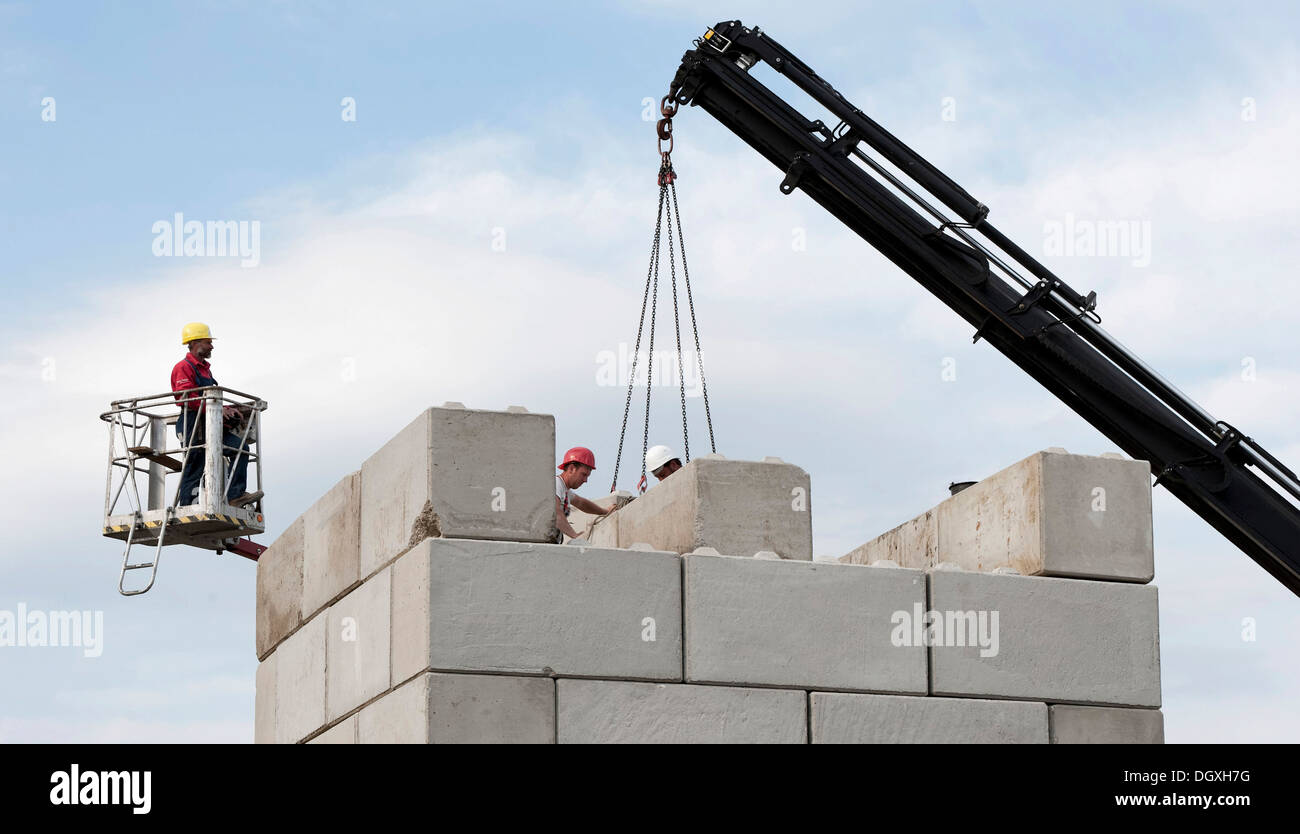 Lavoratori edili di impilamento blocchi di calcestruzzo durante un edificio sito test di carico, sito in costruzione in Fridolfing, Bavaria Foto Stock