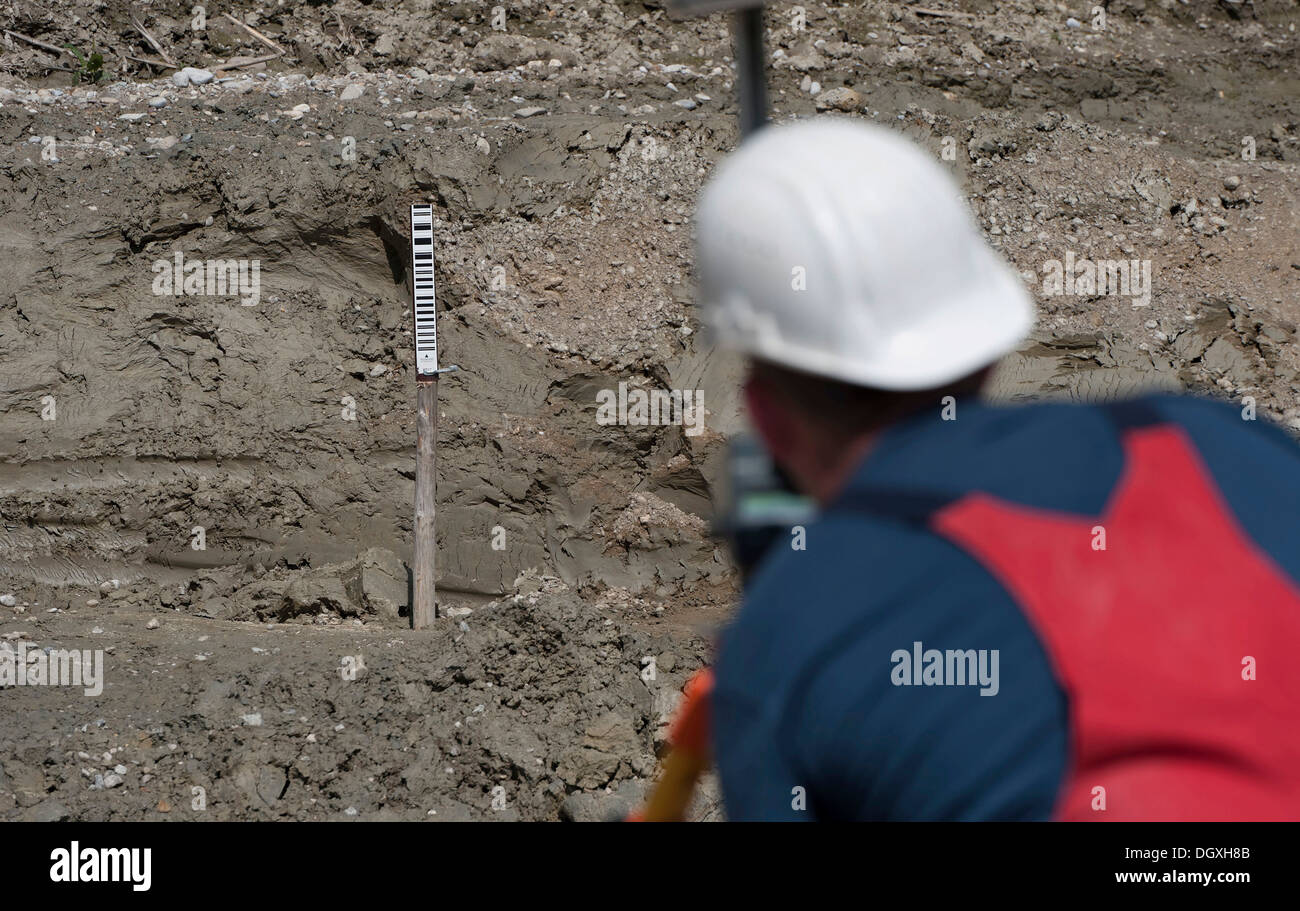 Un ingegnere è prendendo le misure di una possibile caduta del suolo durante un edificio sito test di carico, in corrispondenza di una costruzione Foto Stock