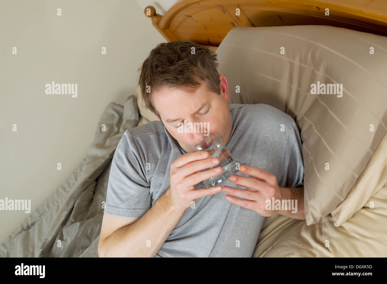 Foto orizzontale di uomo maturo acqua potabile a letto Foto Stock