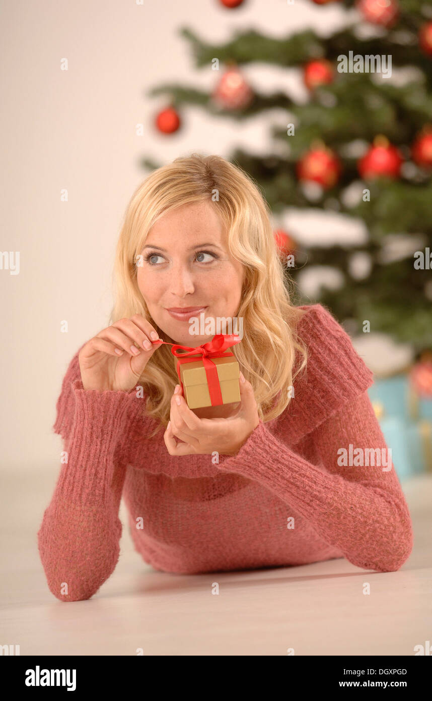 Donna bionda, 20-30, tenendo un golden confezione regalo, ambiente Natalizio Foto Stock