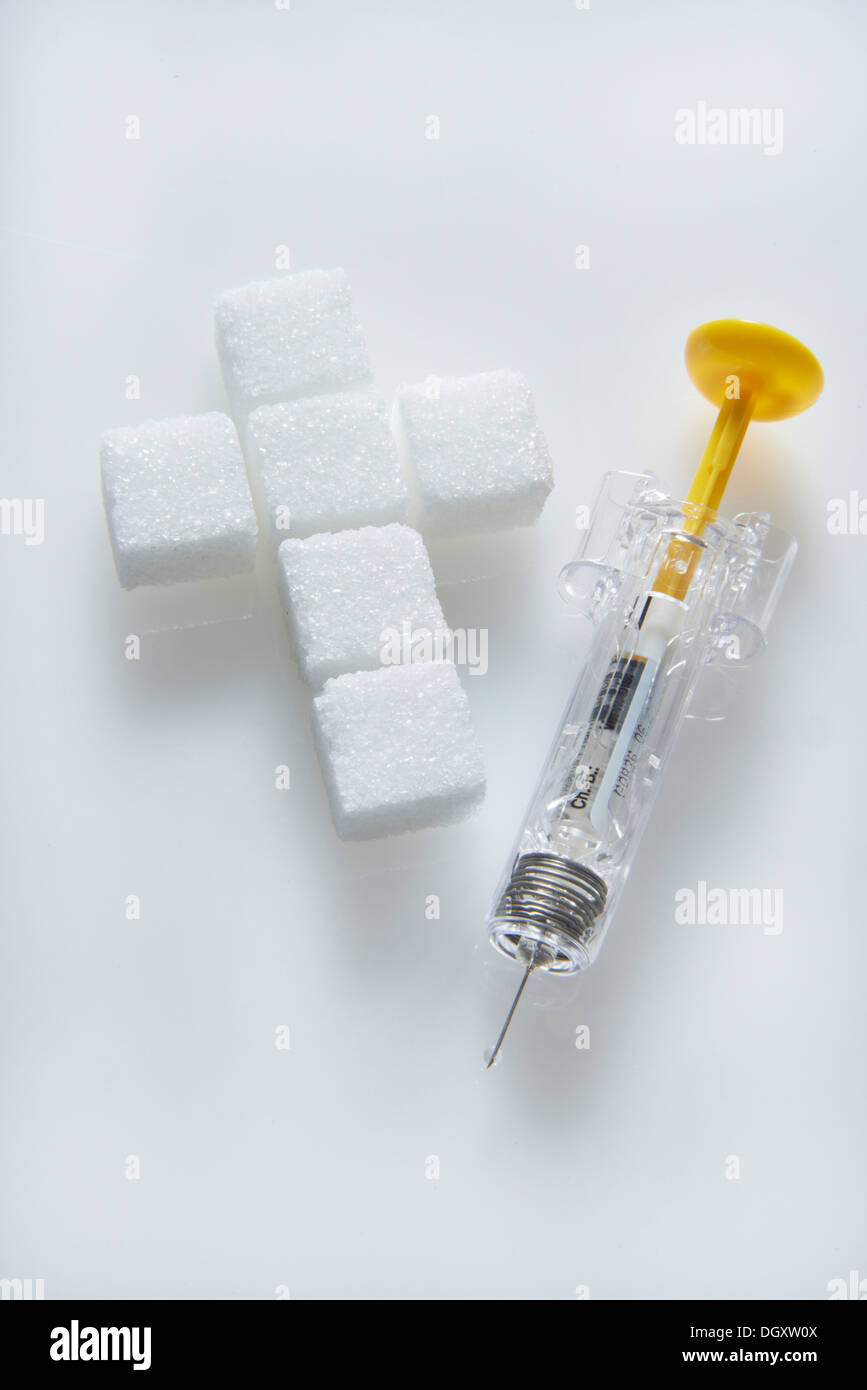 Zollette di zucchero in una forma a croce con una siringa riempita con insulina, iniezione di insulina Foto Stock