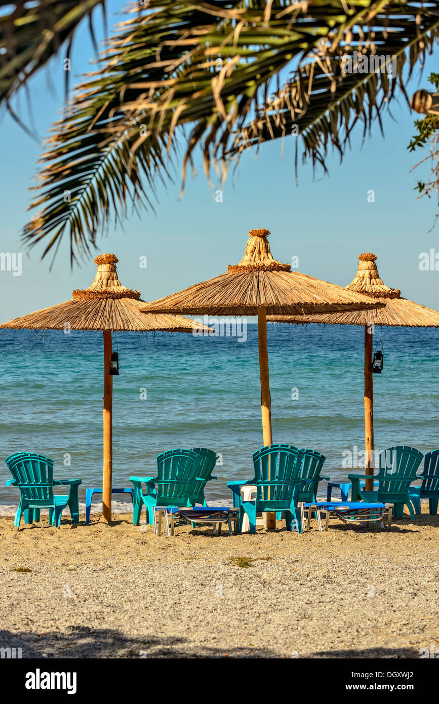 Spiaggia privata con sedie a sdraio e ombrelloni di paglia Foto Stock