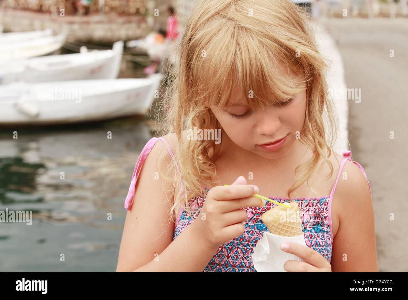 Poco sorridente ragazza bionda mangia gelato. Dehor Estivo ritratto Foto Stock