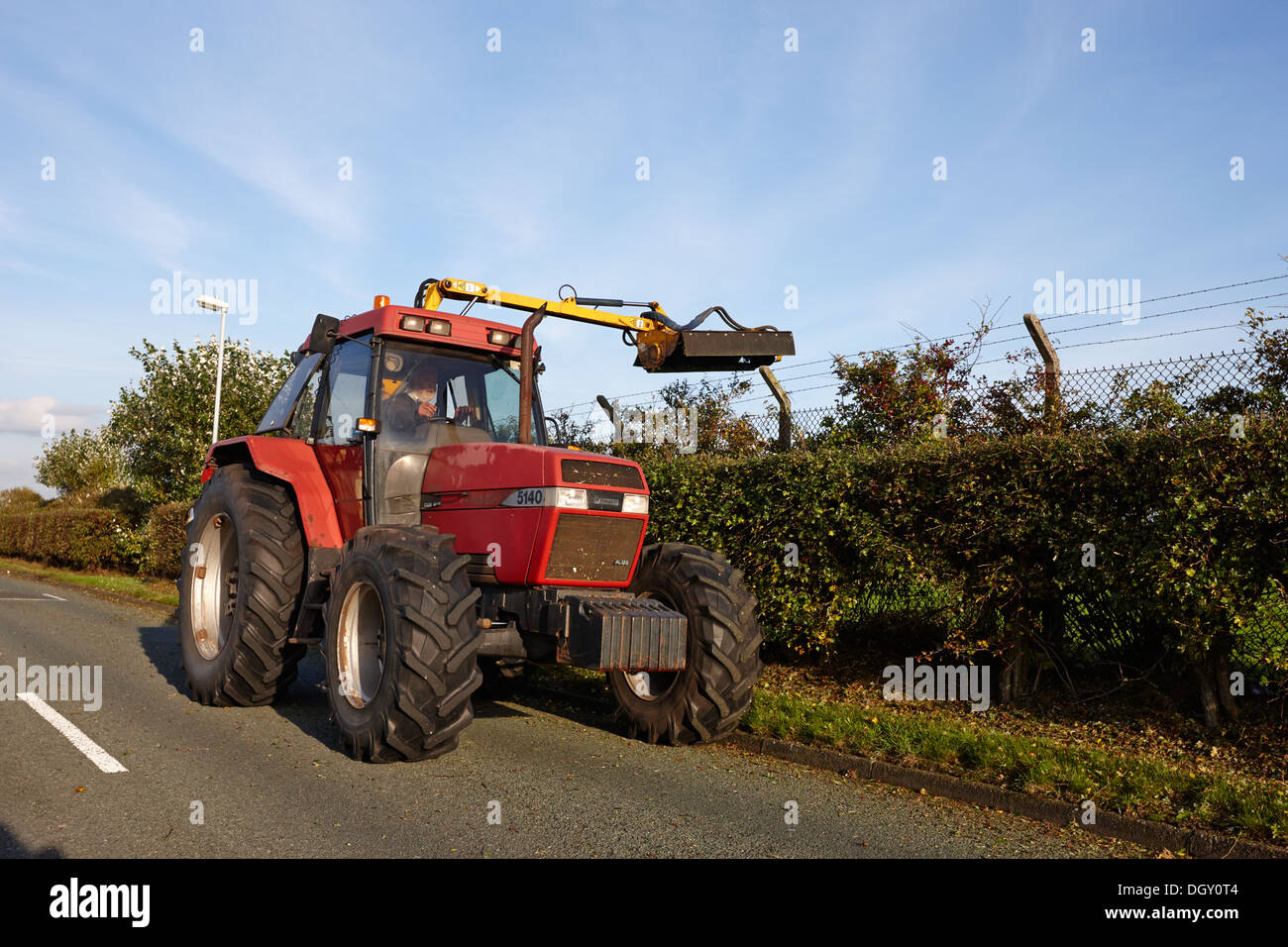 Agricoltore il taglio di siepi di strada con un trattore e attrezzatura Foto Stock