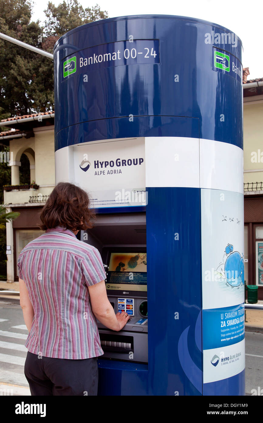Donna spillare denaro da un Bancomat della banca di Hypo Group Alpe Adria in Opatija, Istria, Croazia, Europa, Opatija, Croazia Foto Stock