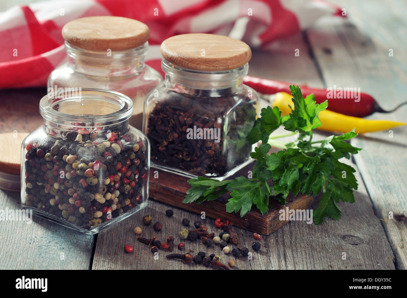 Le spezie in bottiglie di vetro con peperoncino su sfondo di legno Foto Stock