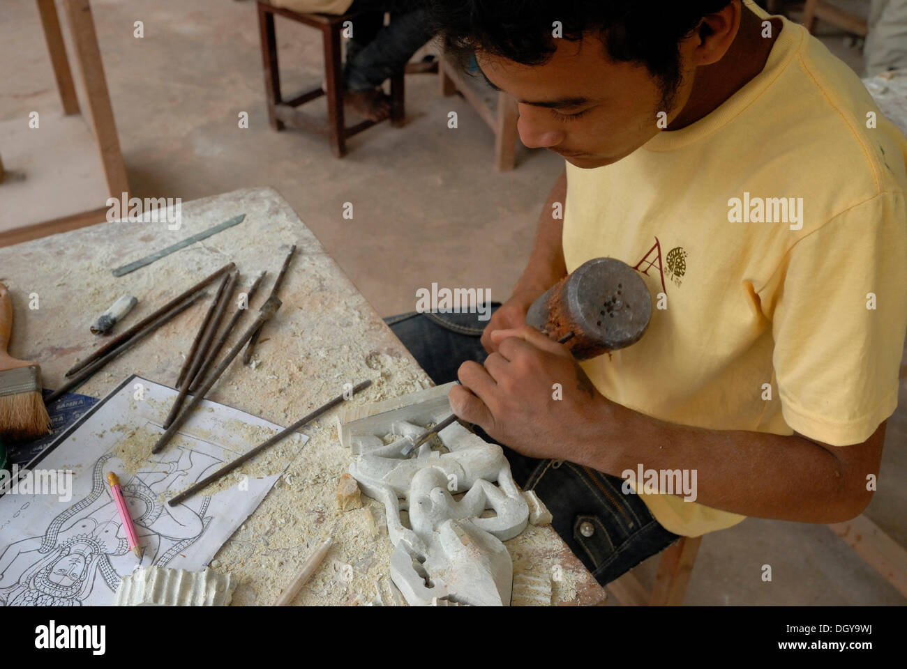 I giovani cambogiani artigiano durante l'artigianato artistico di pietra con un martello di legno e uno scalpello per produrre un tradizionale Foto Stock