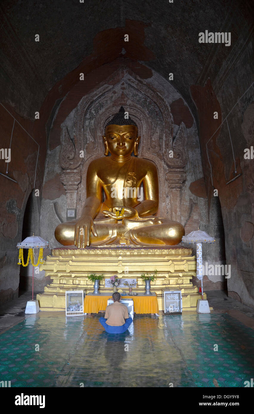 Di birmani uomo seduto, pregando davanti ad un dorato statua del Buddha, Old Bagan, Myanmar o Birmania, Asia Foto Stock