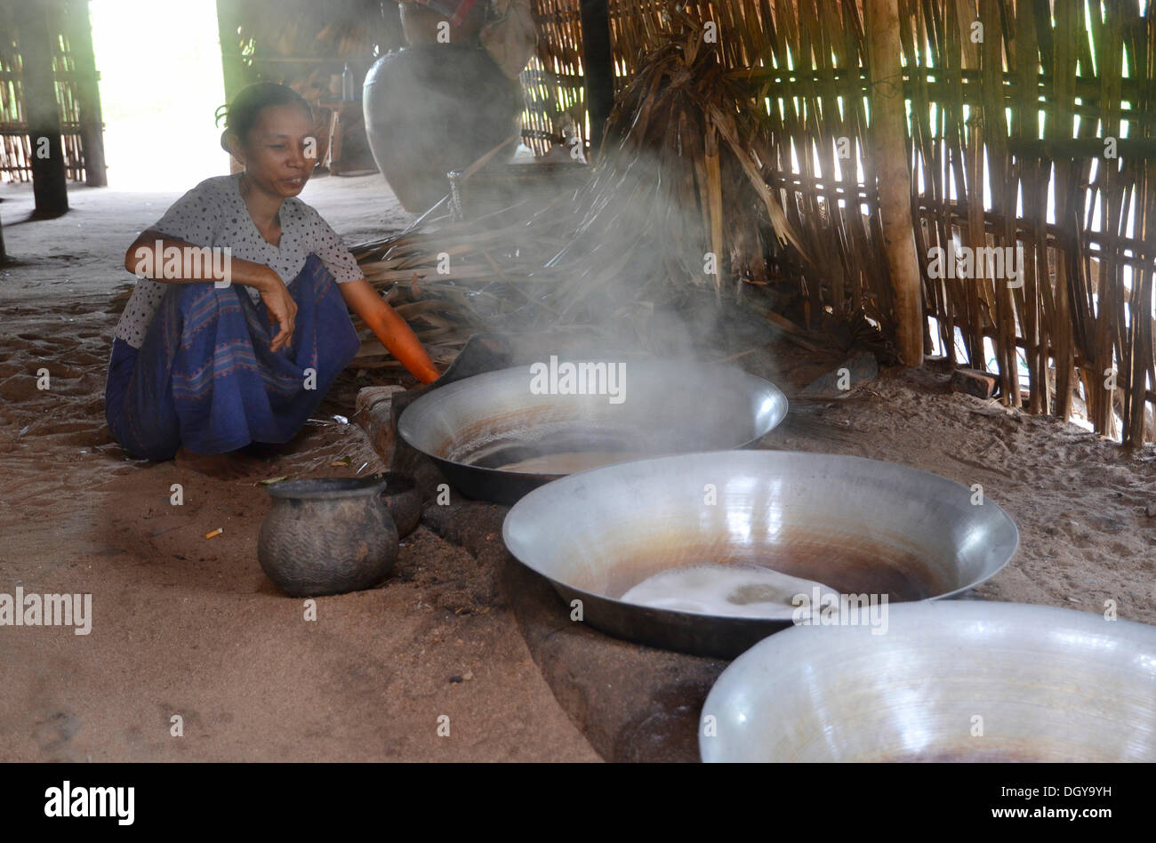 Donna birmano per la cottura su un fuoco aperto, riduzione di succo di Palm per palm zucchero, Bagan, pagano, Myanmar, Birmania, sud-est asiatico Foto Stock