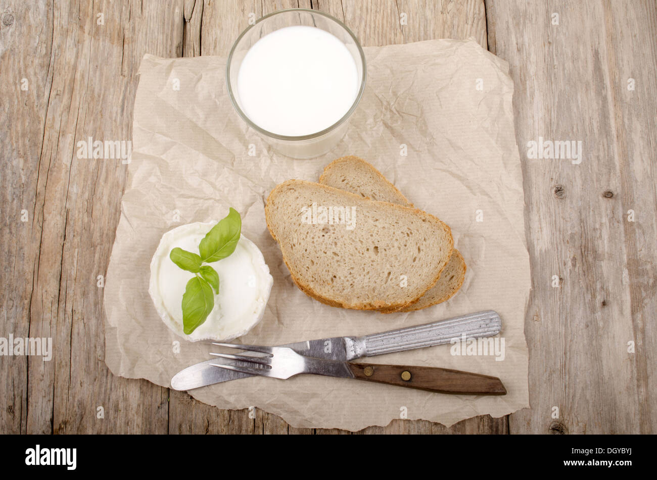 Formaggio di capra, basilico, pane e latte su una country house tavolo da cucina Foto Stock
