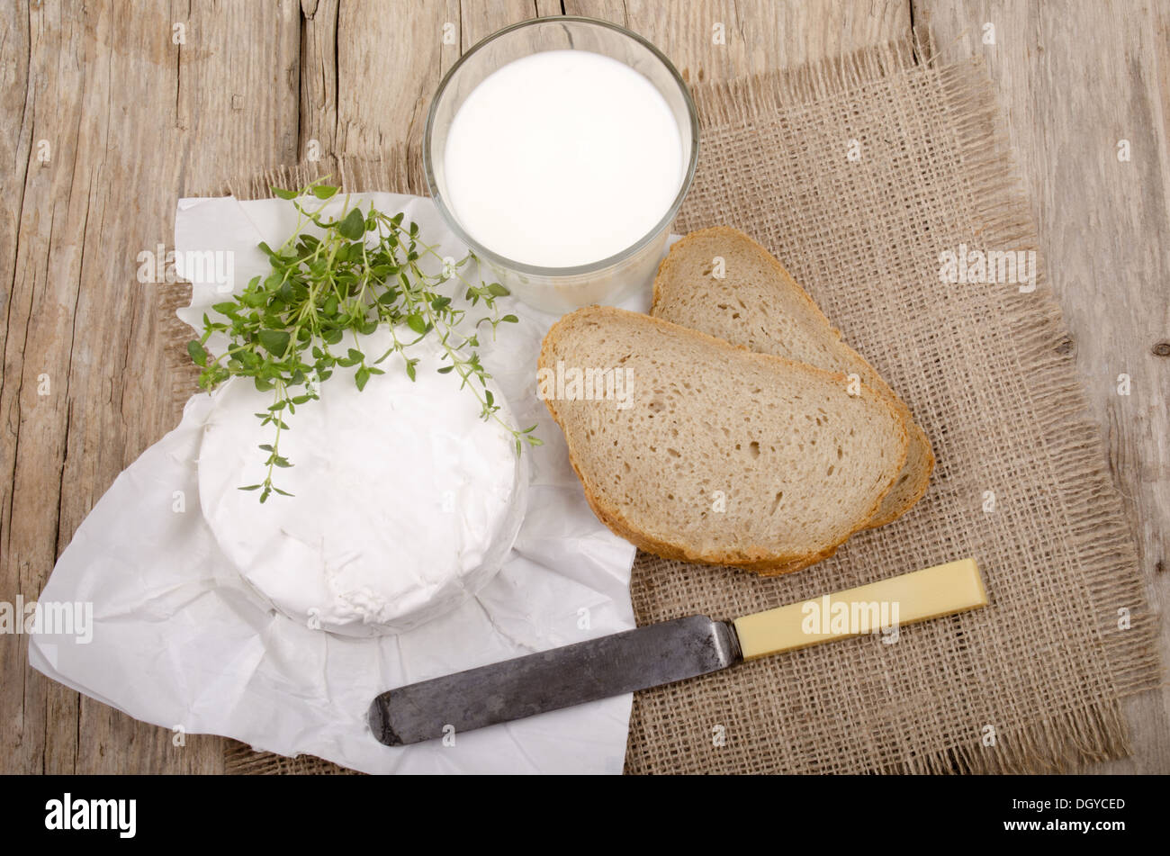 Francese camembert brie con timo, pane e latte su una country house tavolo da cucina Foto Stock