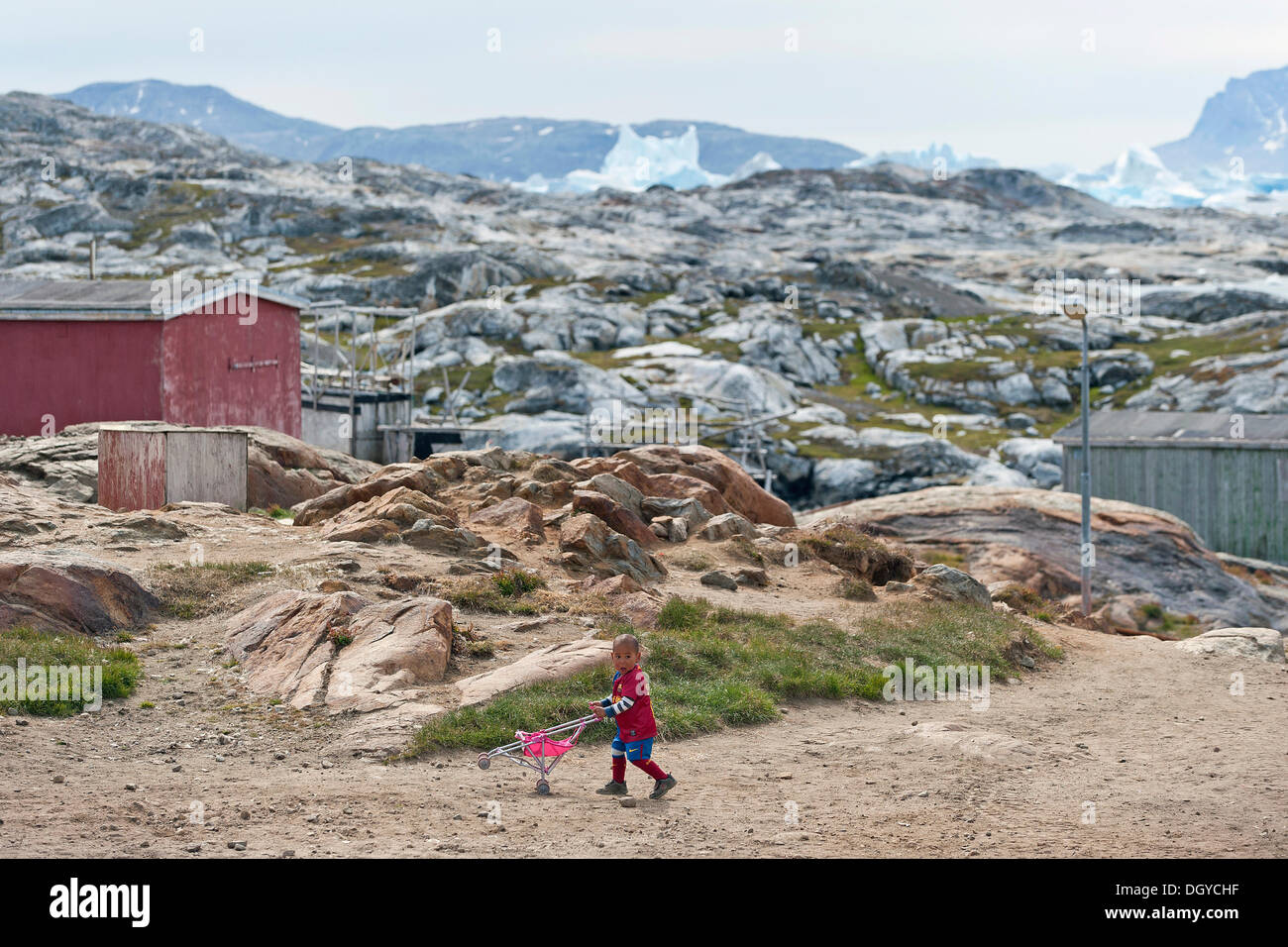 Ragazzo spinge un passeggino giocattolo, Inuit insediamento di Tiniteqilaaq, Sermilik Fjord, est della Groenlandia, Groenlandia Foto Stock