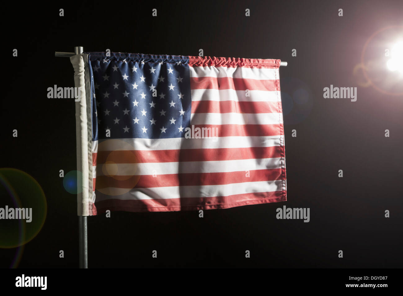 Una bandiera americana contro uno sfondo nero, spot illuminato Foto Stock