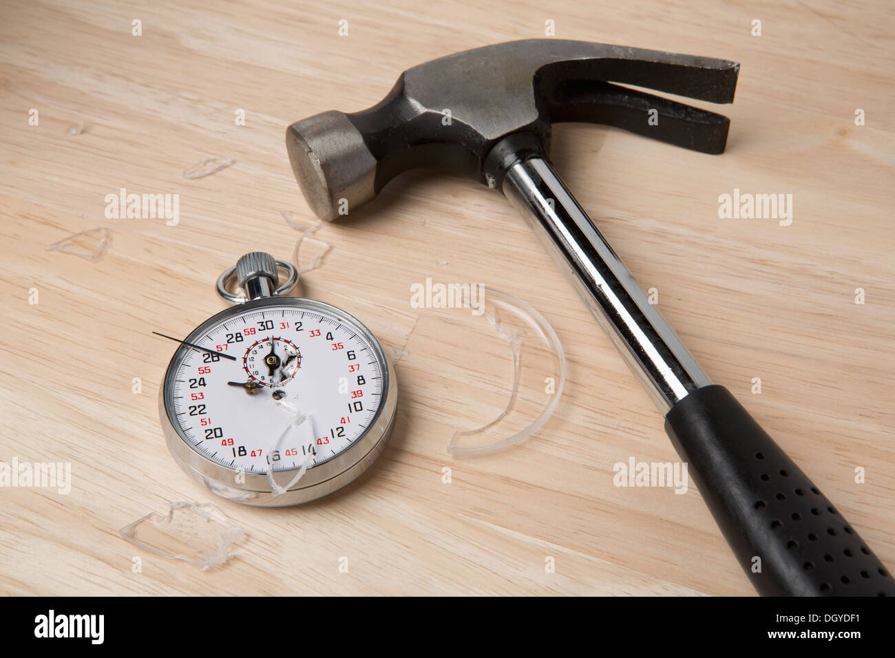 Un martello da carpentiere che giace accanto a un cronometro rotto Foto Stock