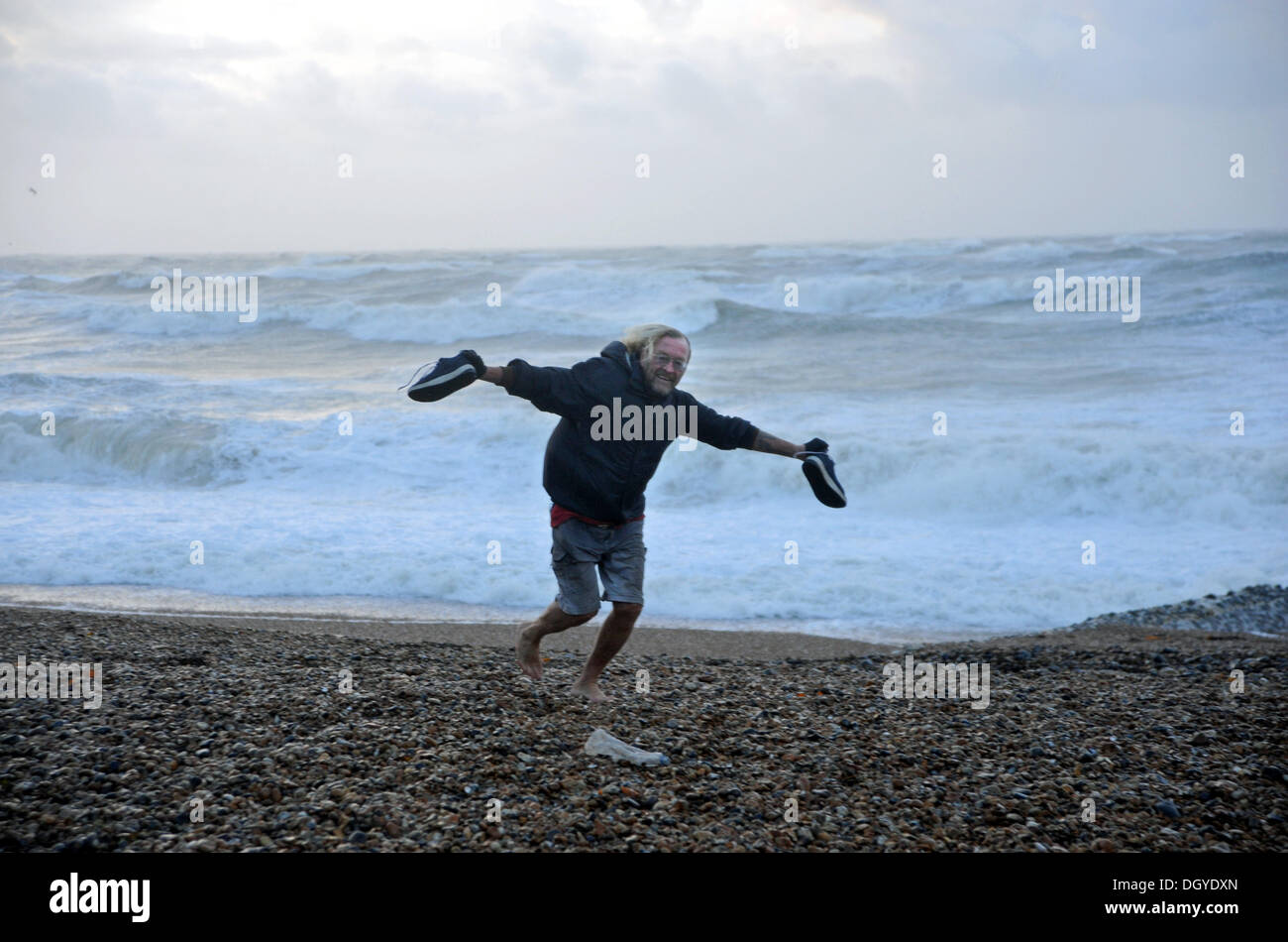 Brighton SUSSEX REGNO UNITO 28 Ottobre 2013 - Questo uomo prende le sue scarpe e calze di come egli passa per una passeggiata sulla spiaggia di Hove come tempeste martoriata costa sud di questa mattina la tempesta, denominato St Jude, ha portato la windiest meteo a colpire il Regno Unito dal 1987. Foto Stock