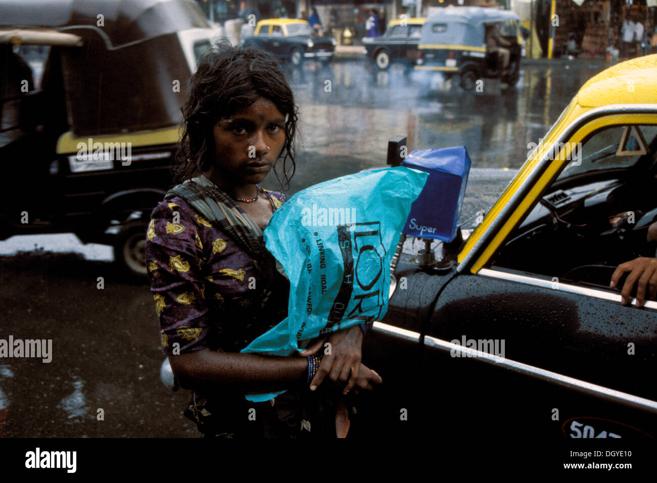 Mendicante femmina in piedi di fronte a un taxi sotto la pioggia, il monsone, Mumbai o Bombay, Maharashtra, India, Asia del Sud, Asia Foto Stock