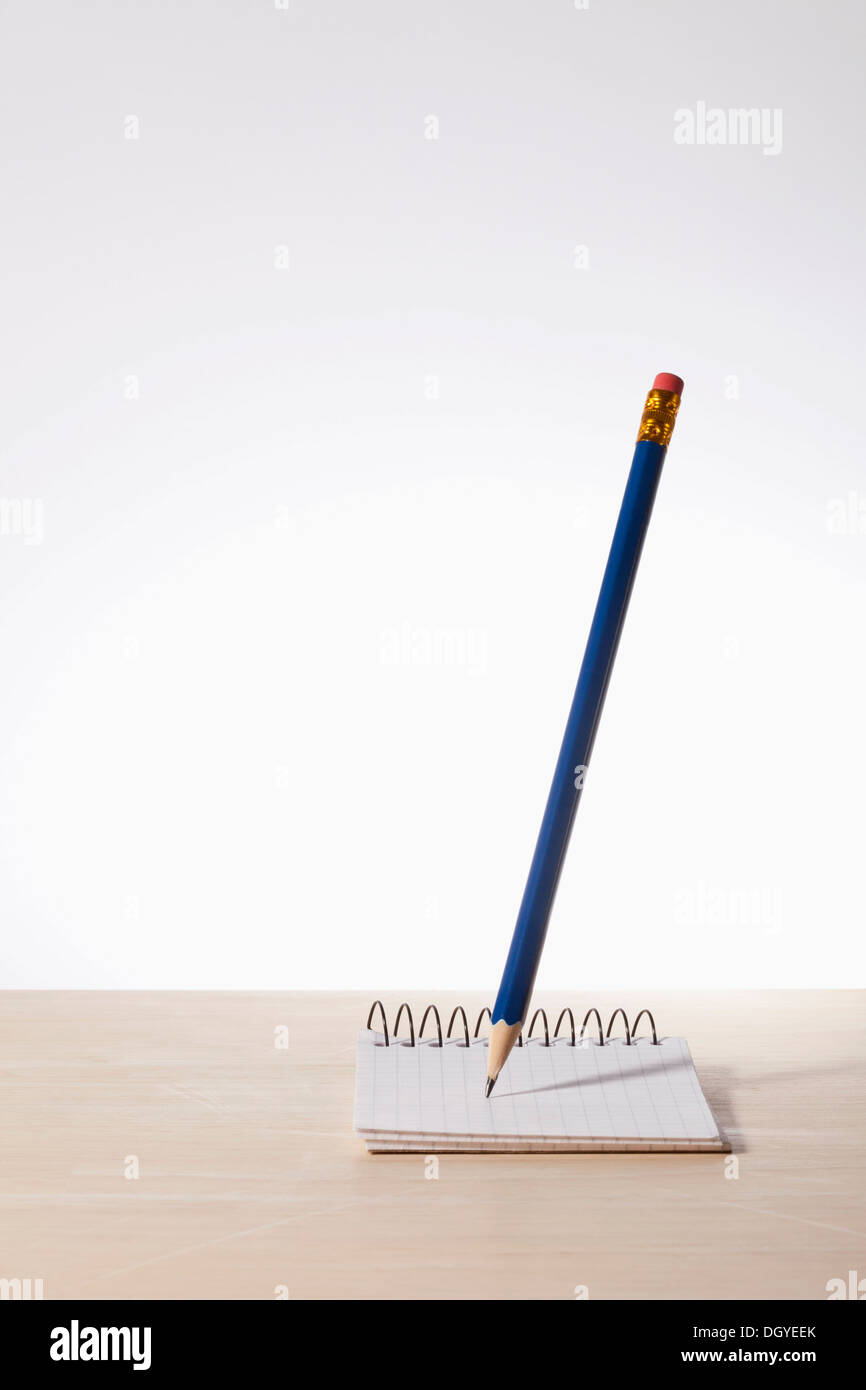 Una matita in bilico sopra un foglio di carta millimetrata blocco note a spirale Foto Stock