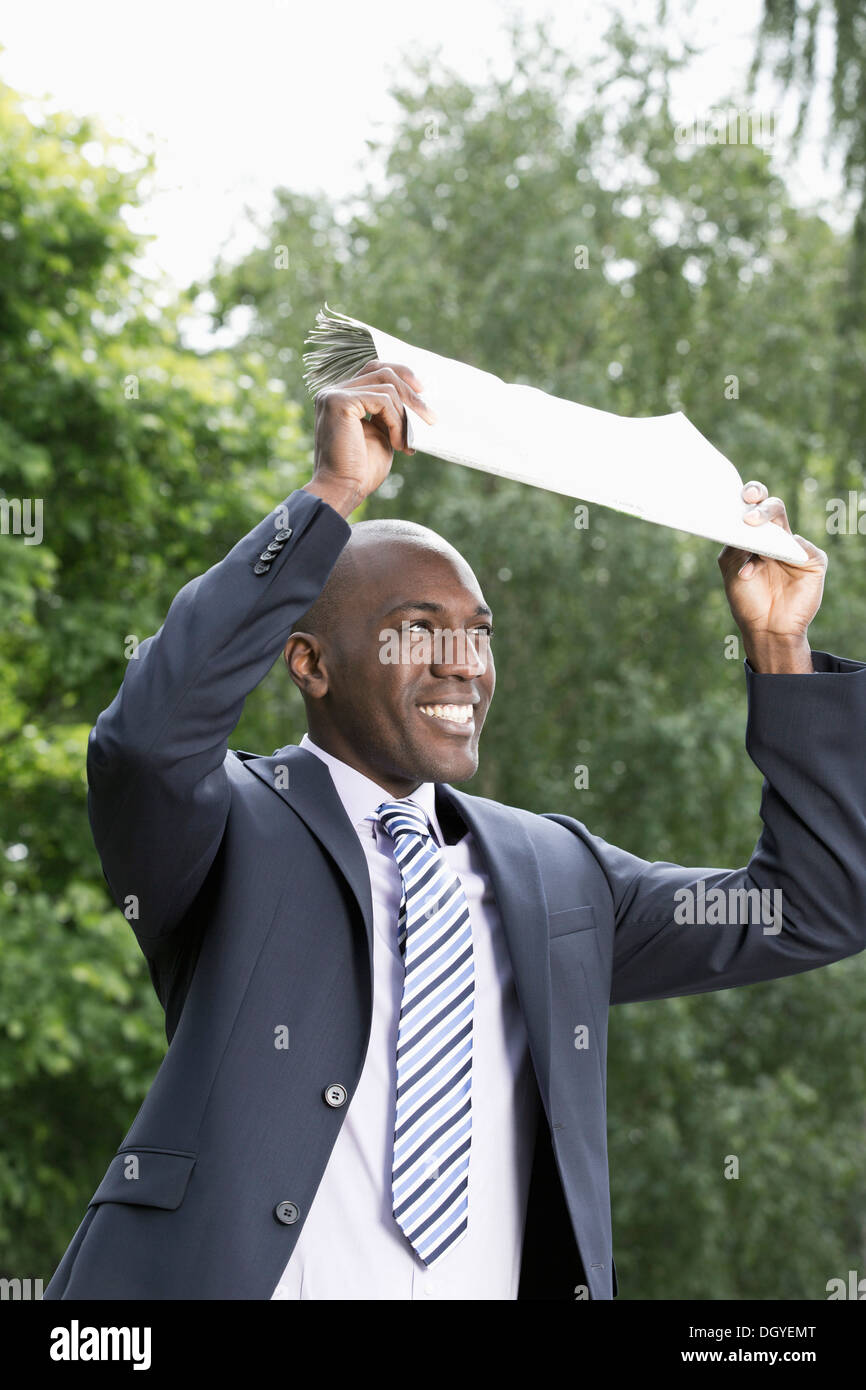 Happy businessman holding giornale sopra la testa Foto Stock