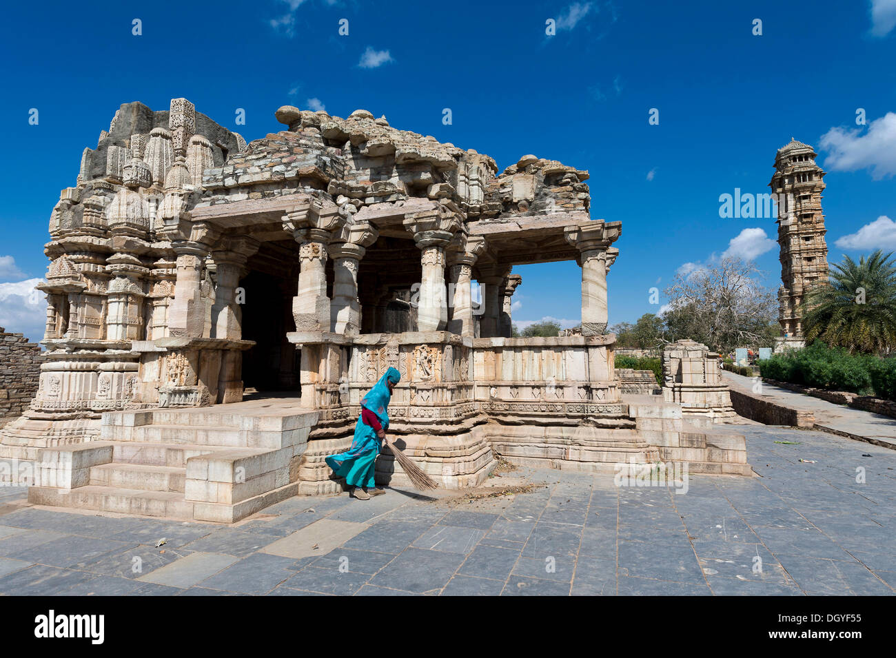 La donna a spazzare le lastre di pietra di fronte i resti di un tempio, Vijaya Stambha, una vittoria a torre costruito durante il regno di Rana Kumbha Foto Stock