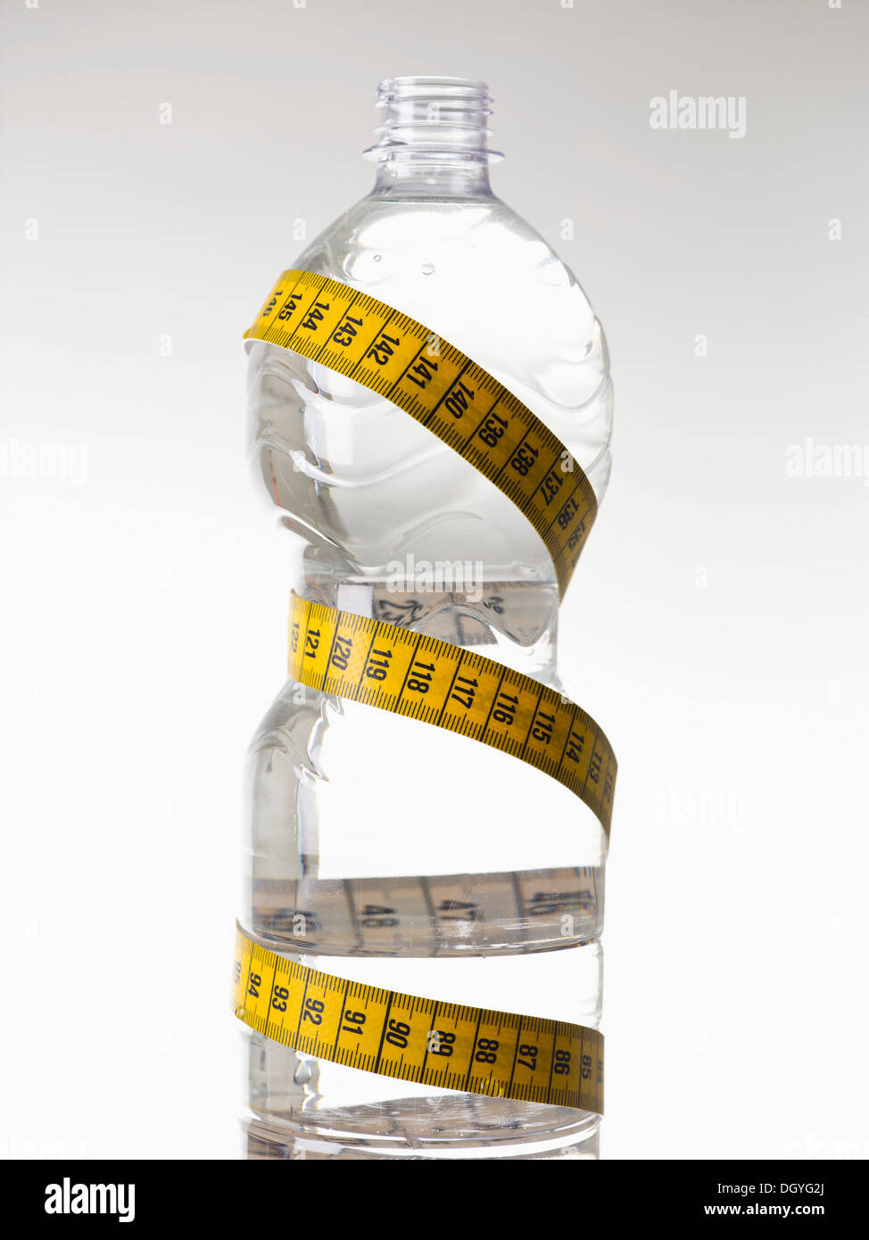 Una bottiglia d'acqua in plastica pieno di acqua e avvolto con un nastro di misurazione Foto Stock