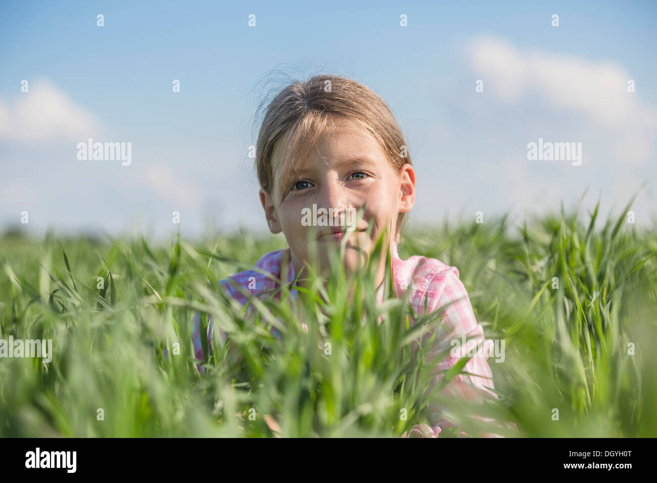 Una giovane ragazza sorridente giacente in erba su un giorno d'estate Foto Stock