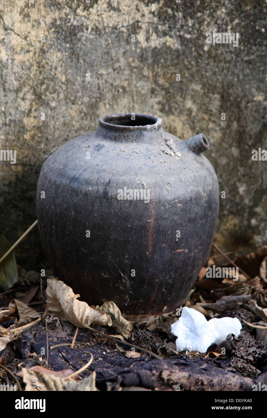 Si tratta di una foto di un vaso o contenitore di liquido che è vecchio e soggiorno contro una parete Foto Stock