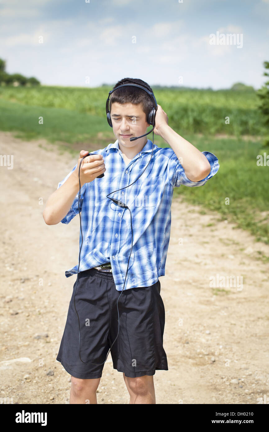 Ragazzo con cuffie e microfono sulla strada rurale Foto Stock