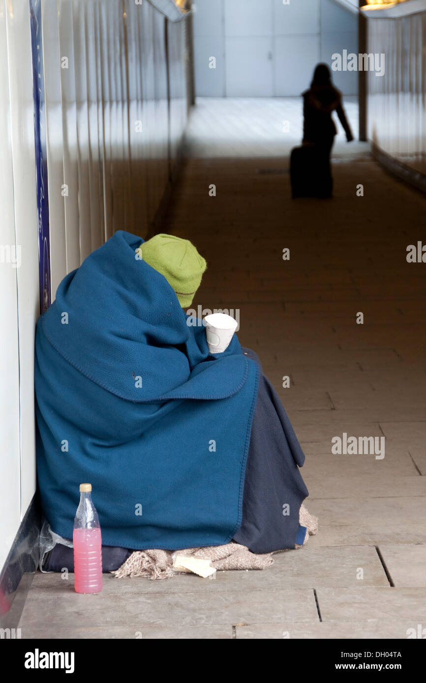La persona senza dimora avvolto in un manto seduto in un sottopassaggio, Londra, regione di Londra, England, Regno Unito Foto Stock