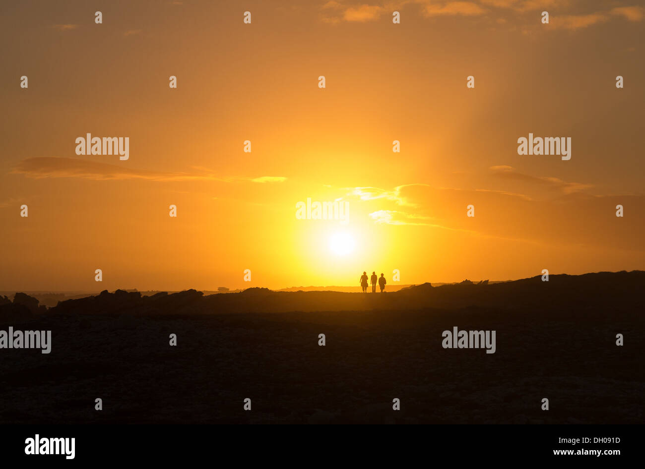 Tre persone a piedi direttamente nel sole al tramonto a Capo Agulhas sud la maggior parte della punta del Sud Africa Foto Stock