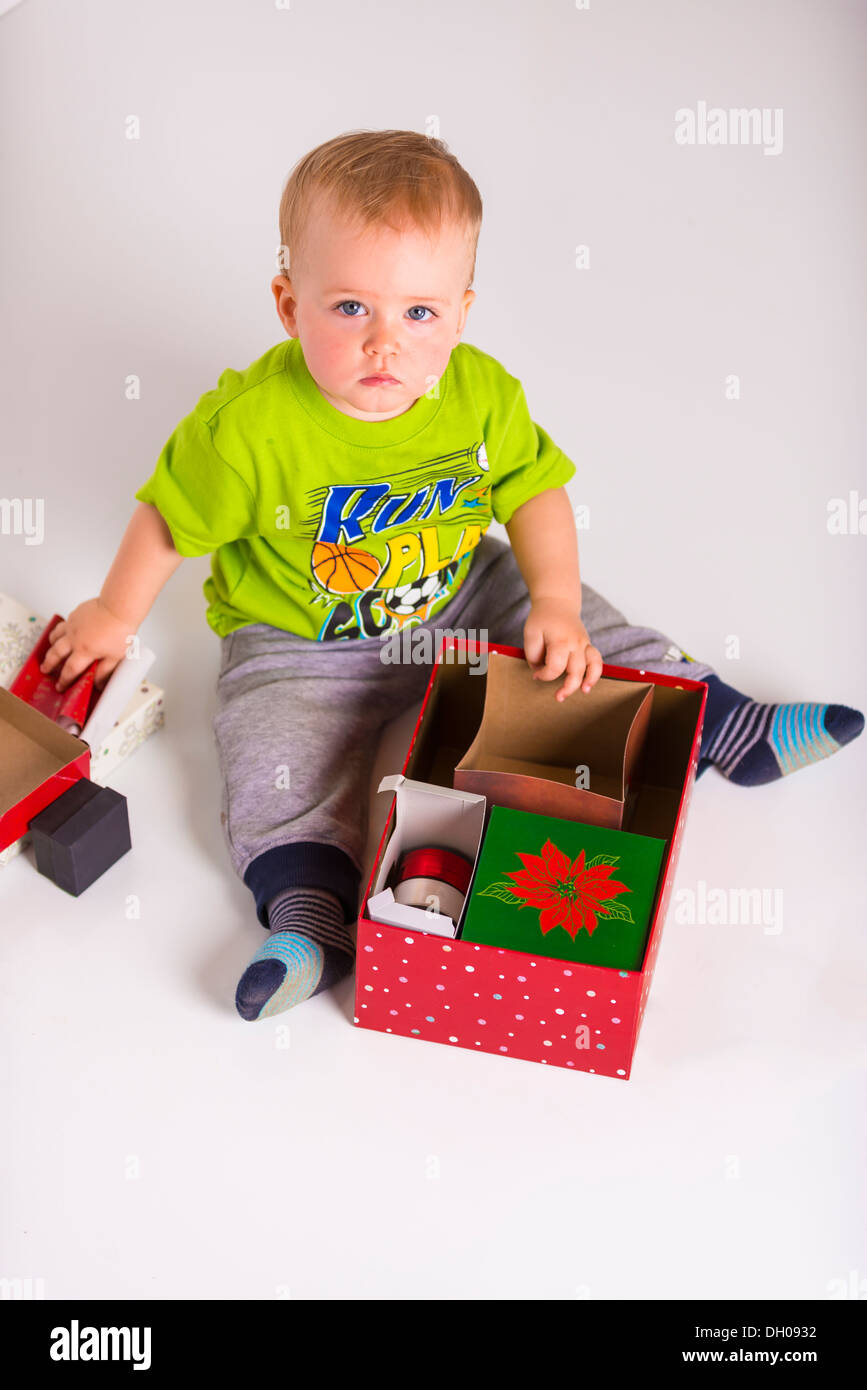 Un maschio caucasico bambino di età compresa tra uno e due anni sembra essere colti sul fatto di apertura presente una scatola di cartone. Foto Stock