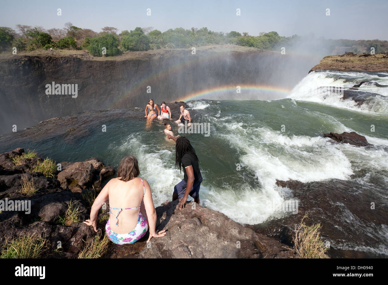 Turisti Zamnia; persone che nuotano nella Devils Pool ai margini delle Cascate Vittoria, viaggio avventura in Zambia Africa Foto Stock