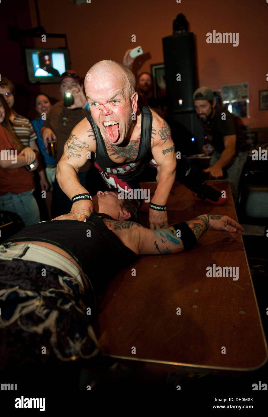 Stevie "Puppet" della "mezza pinta di lottatori' psycho midget wrestling, tiene giù Eric 'Smallz' su un tavolo al di fuori dell'anello. Foto Stock