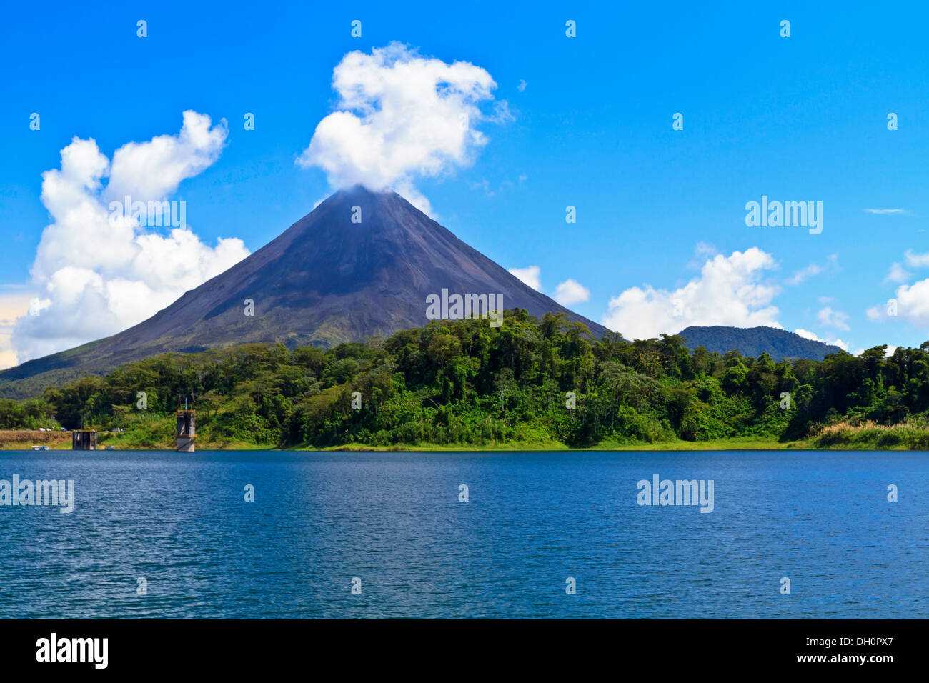 Il Vulcano Arenal 'soffi' fuori una nuvola sopra la foresta pluviale sulle rive del Lago di Arenal in Costa Rica Foto Stock