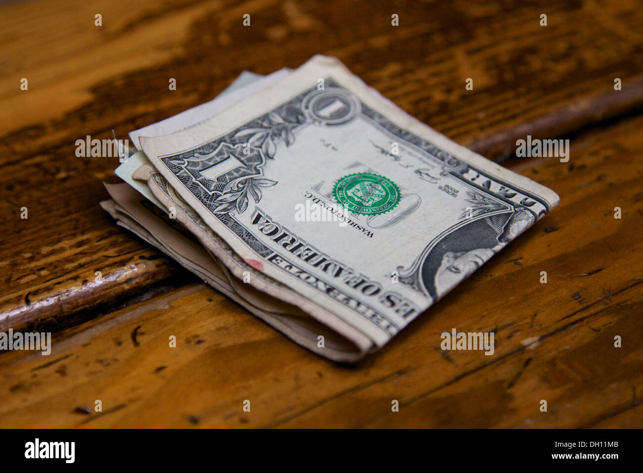 Bundle ripiegata di ben utilizzato dollar note su un usurato bar in legno. Foto Stock