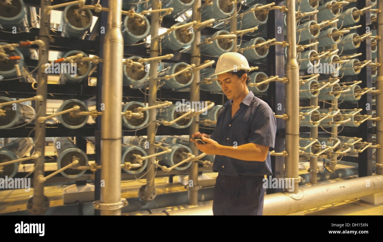 Lavoratore ispanica con un telefono cellulare in magazzino Foto Stock