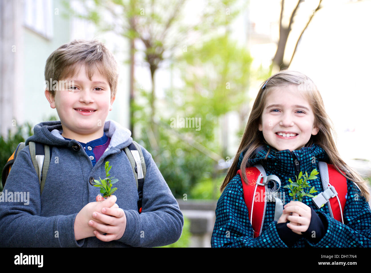 Due bambini di andare a scuola a piedi, tenendo evergreen ramoscelli, Monaco di Baviera, Germania Foto Stock
