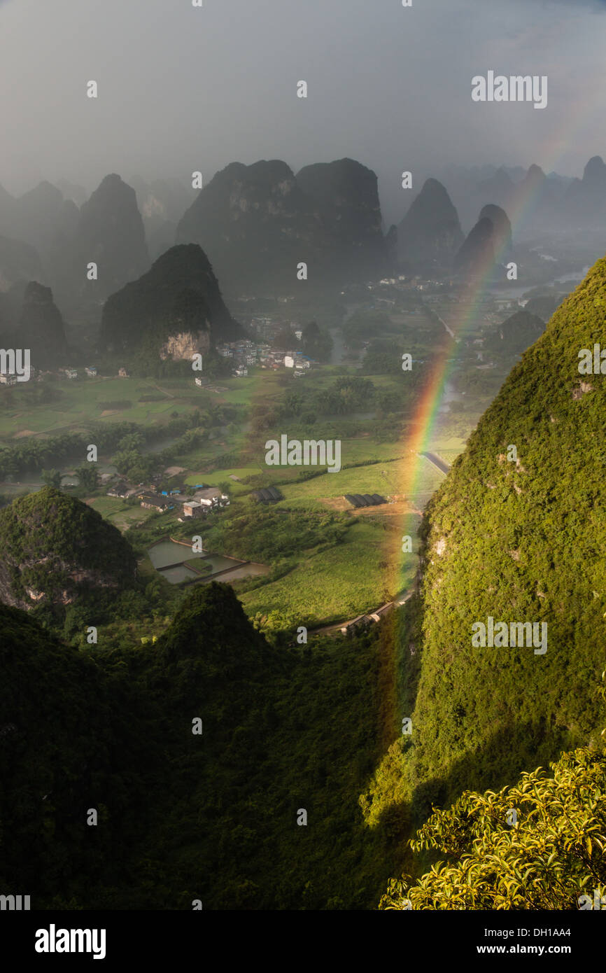 Un arcobaleno allineato con un picco del carso durante una doccia a pioggia al di fuori di Yangshuo, Cina del Sud Foto Stock