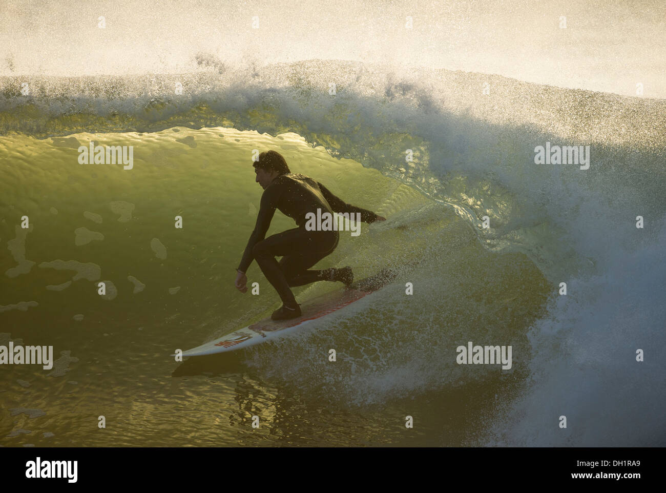 Surfer lo stallo nel tubo, false bay, luci del tramonto Foto Stock