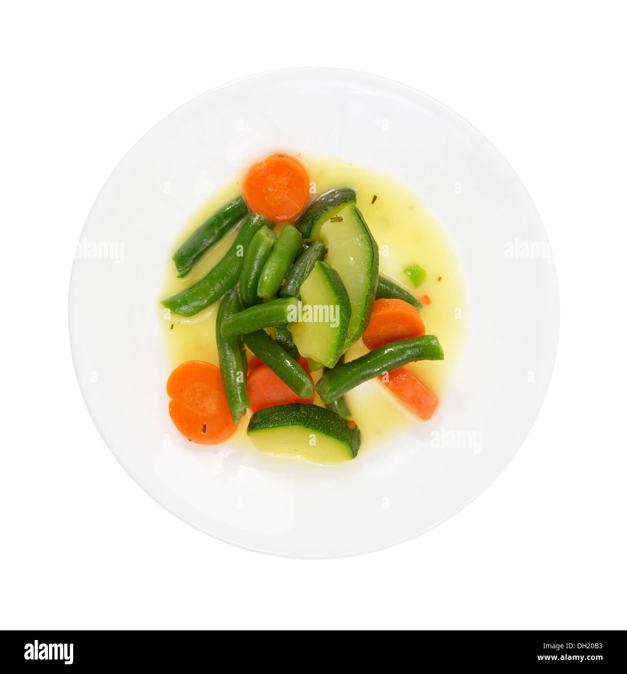 Vista dall'alto di un piatto cucinato con zucchine, carote e fagioli verdi in una salsa di burro su uno sfondo bianco. Foto Stock