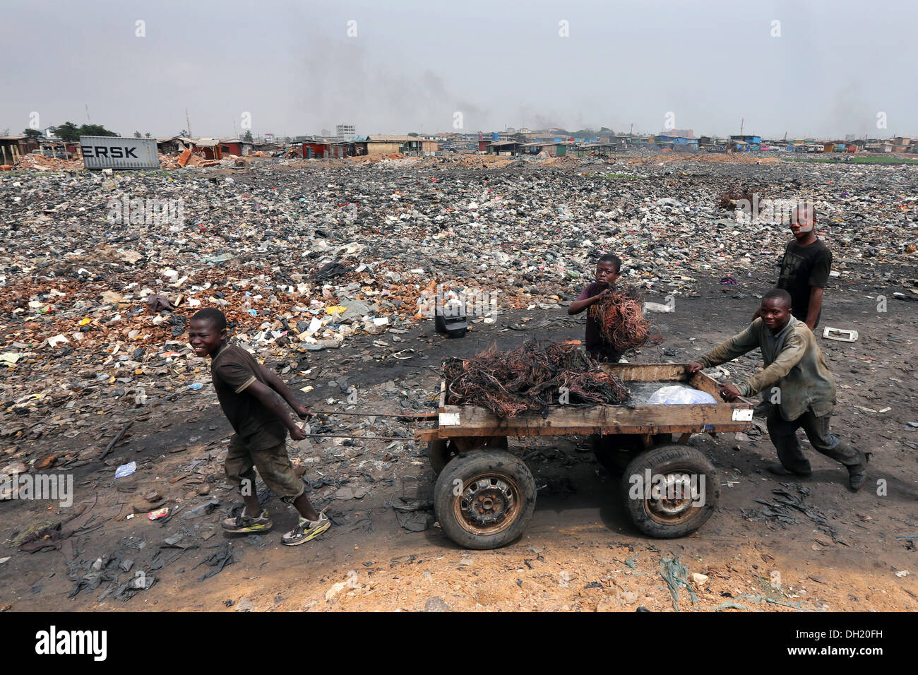 Ragazzi tirare un carrello a crudo con cavi in rame bruciato dal computer, Agbogbloshie discarica di Accra, in Ghana Foto Stock