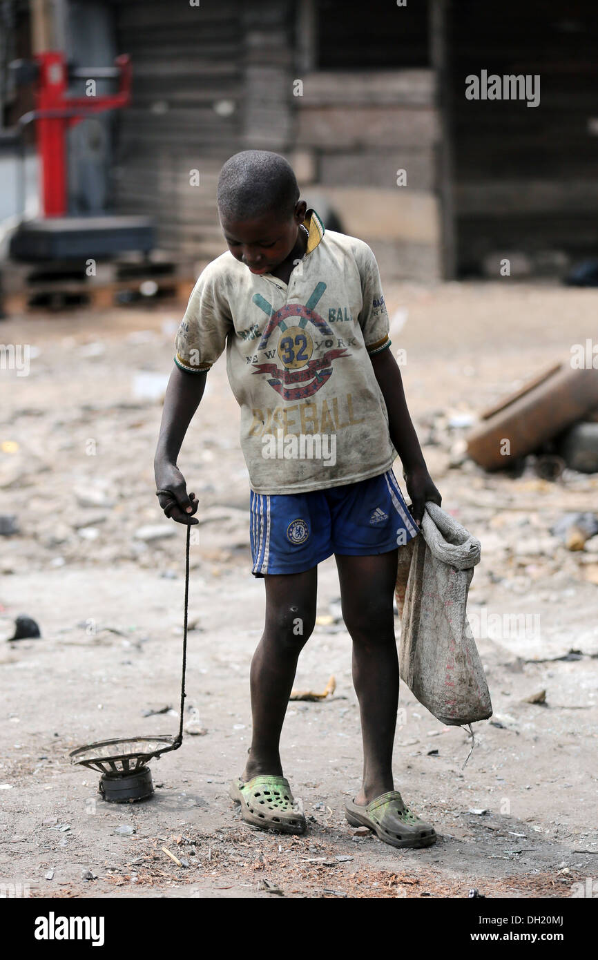 Ragazzo raccoglie pezzi di ferro con un magnete sull'immondizia elettronica Agbogbloshie dump, Accra, Ghana Foto Stock