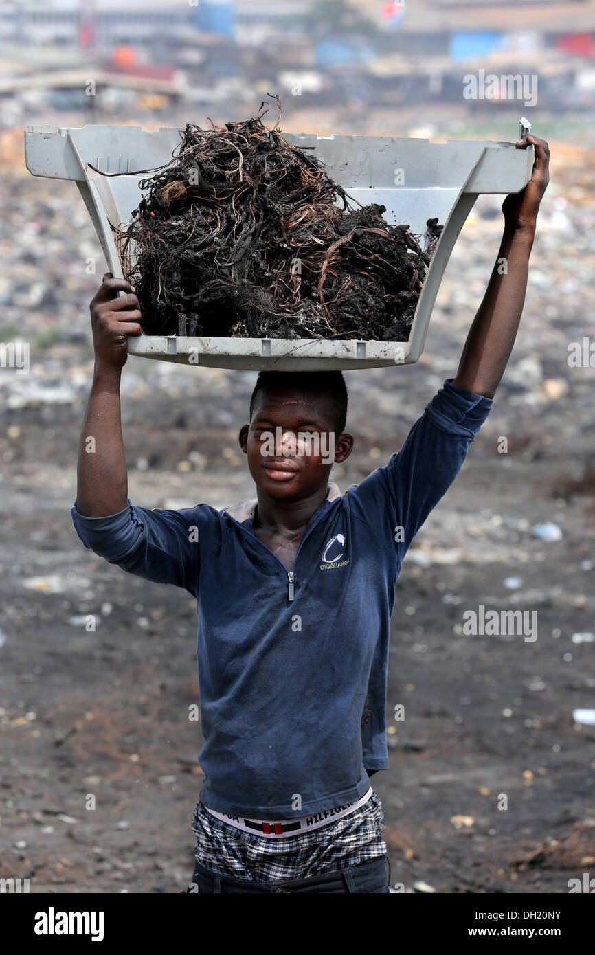 Ragazzo adolescente porta raw cavi di rame dal computer bruciati, Agbogbloshie discarica di Accra, in Ghana Foto Stock