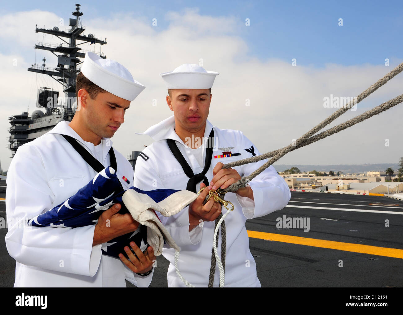 Airman Brandon dolce, sinistra, da Foxboro, Massachusetts, e aviazione Ordnanceman 3° di classe Mario Mendoza, da Norwalk, California, prepara ad alzare la bandiera americana sul ponte di volo della portaerei USS Ronald Reagan (CVN 76). Ronald Reagan è ormeggiata e Foto Stock