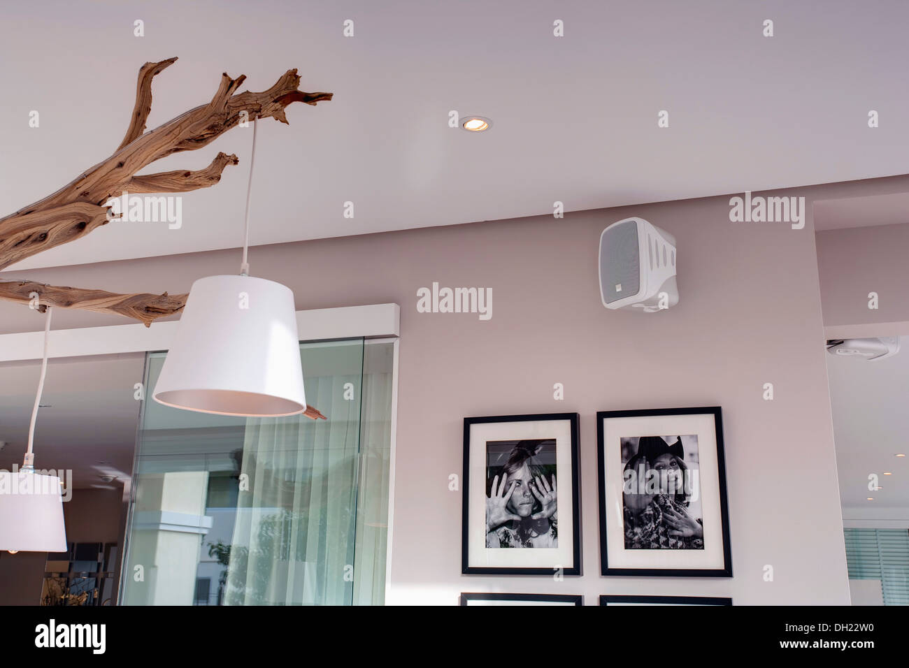 Paralumi bianco appeso dal rustico ramo di albero in spagnolo moderno sala da pranzo con nero incorniciate+fotografie in bianco Foto Stock