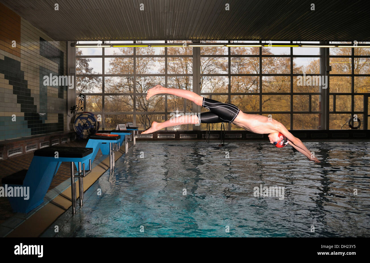Il ragazzo, nuotatore, dodici o tredici anni, saltando dal blocco di partenza in piscina Foto Stock