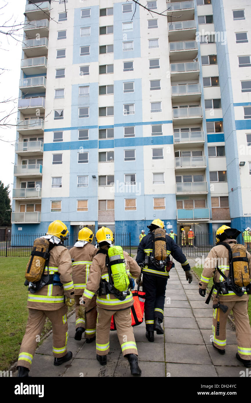 Un sacco di vigili del fuoco a piedi verso l'alto edificio appartamenti appartamento blocco Foto Stock