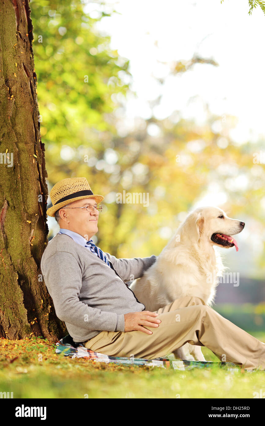 Senior gentleman e dog sitter su terra e in posa di un parco Foto Stock