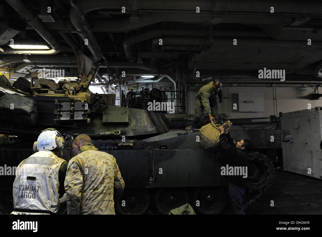 Marinai e Marines ingranaggio di scarico da un M1A1 battaglia principale serbatoio a bordo del multipurpose Amphibious Assault nave USS Bataan (LHD 5). Foto Stock